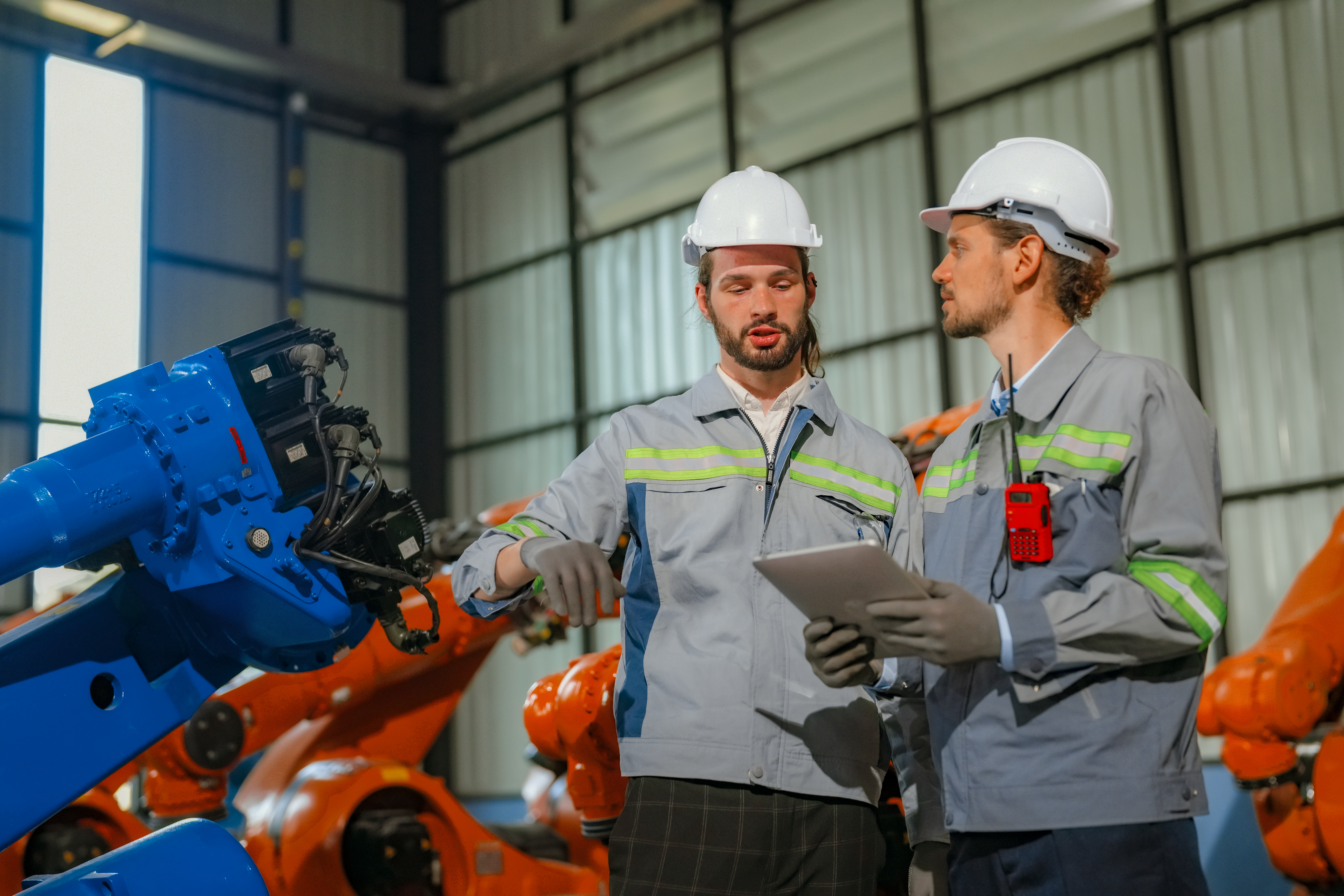 Robotics engineers reviewing maintenance work beside industrial robot arms
