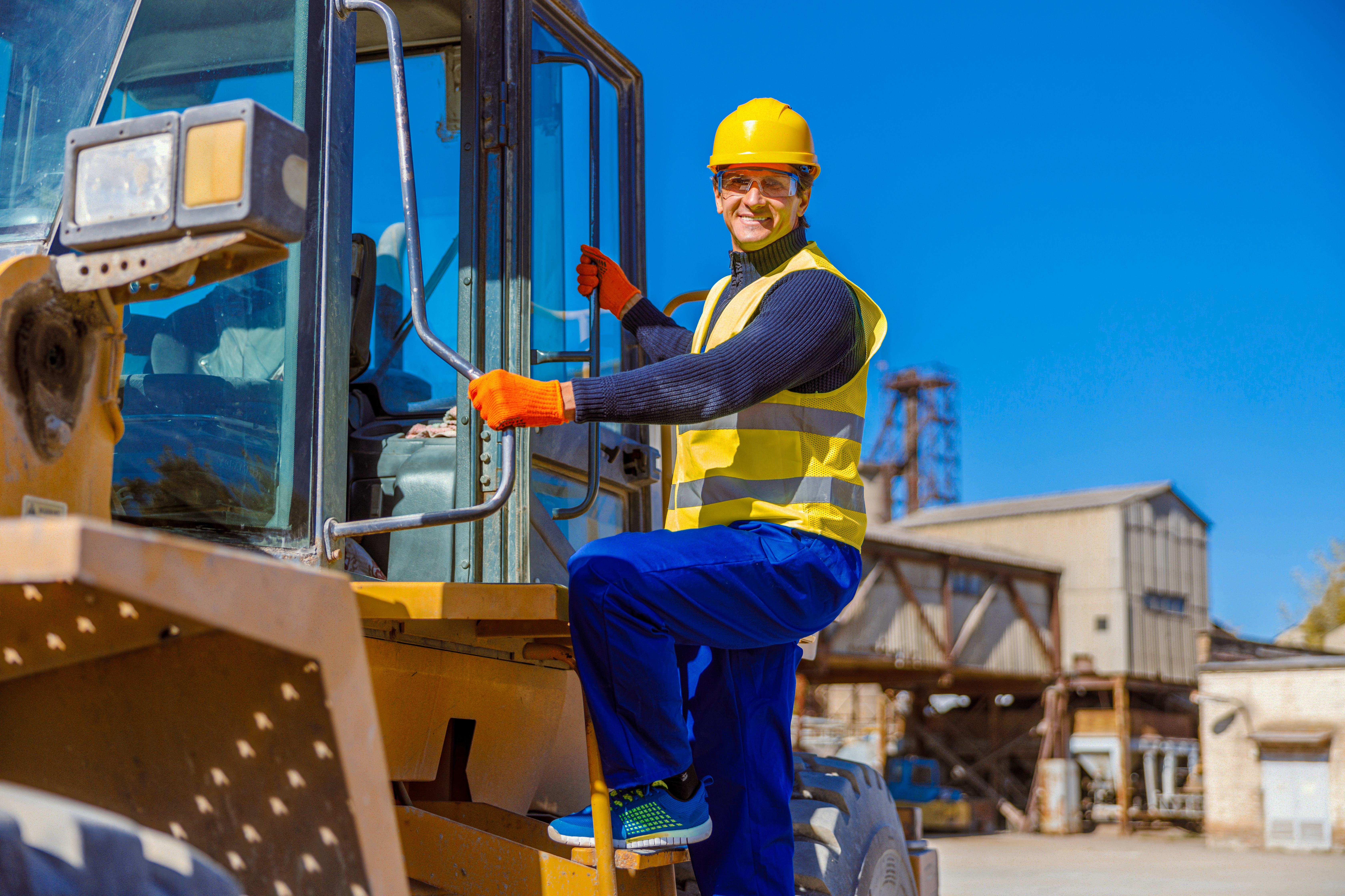 Construction professional positioned around heavy equipment on an active industrial site