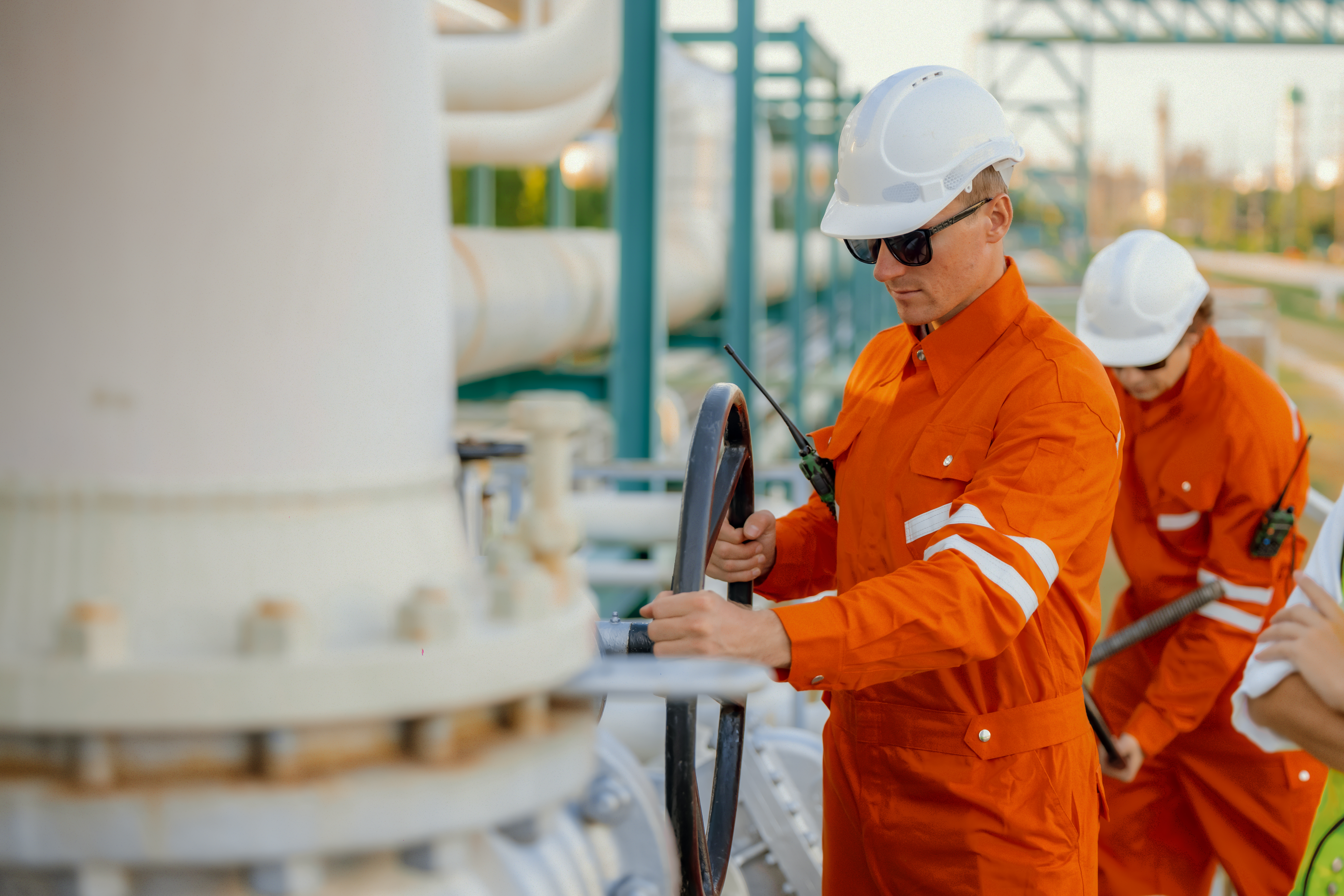 Oil refinery operator turning a process valve while following site procedures